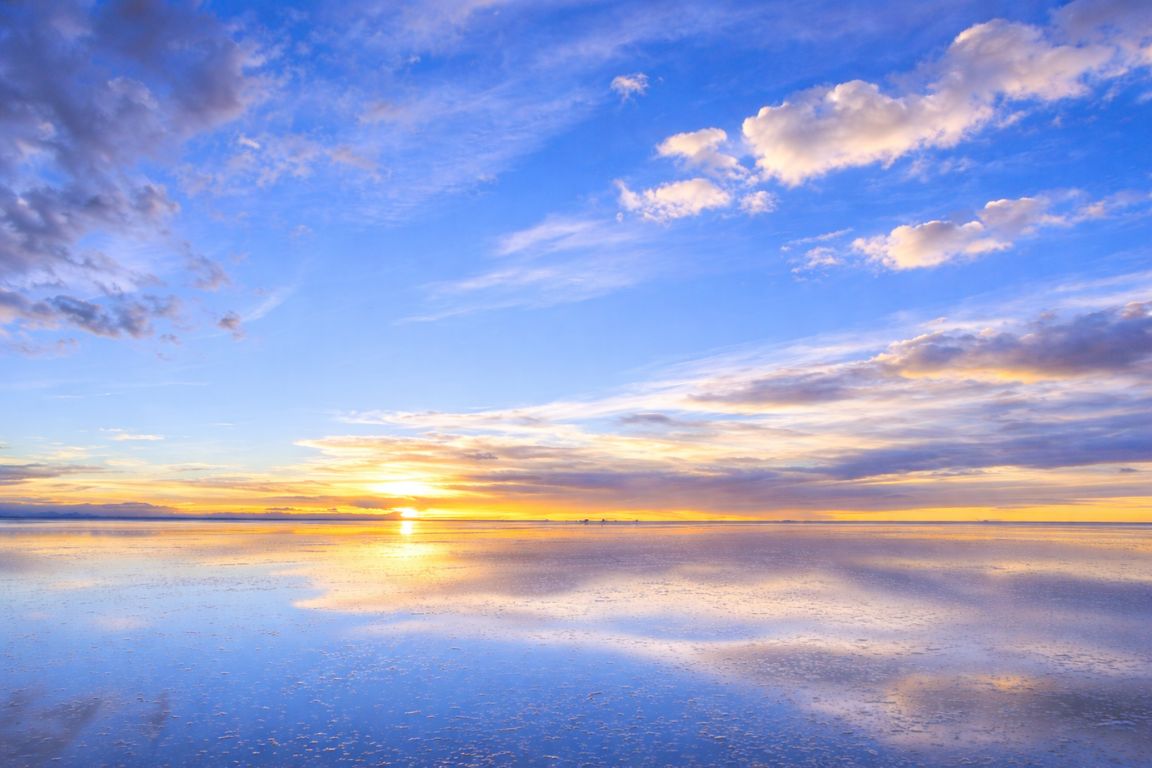 Sunset mirror effect on Salar de Uyuni with sky perfectly reflected on water-covered salt flats, captured during a tour with Salar de Uyuni Tours